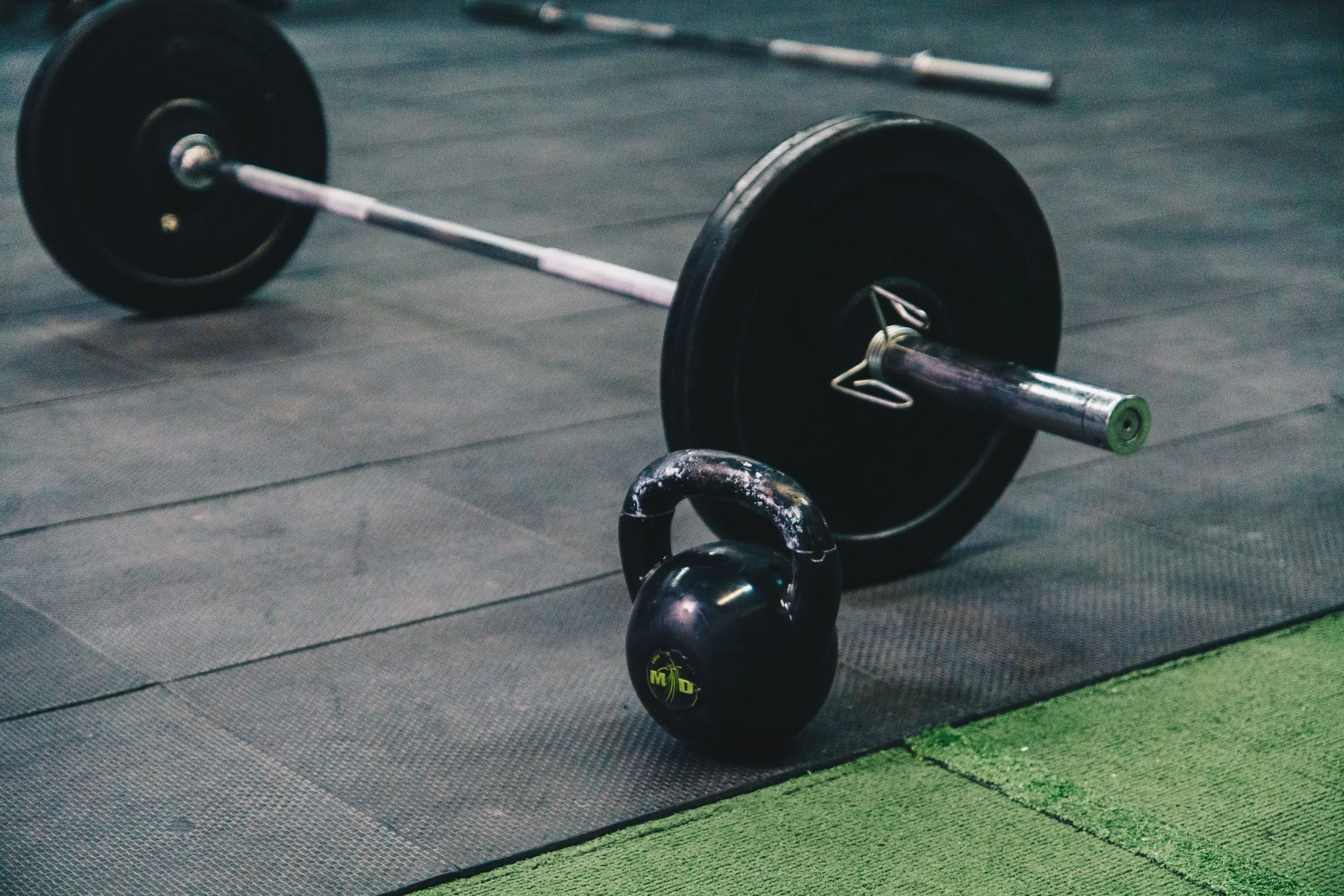 Halter met gewichtsschijven en een kettlebell op de rubberen sportvloer